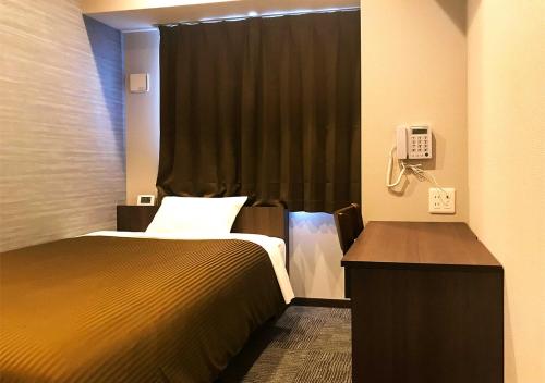 een hotelkamer met een bed en een telefoon bij Hotel Trend Omiya in Saitama