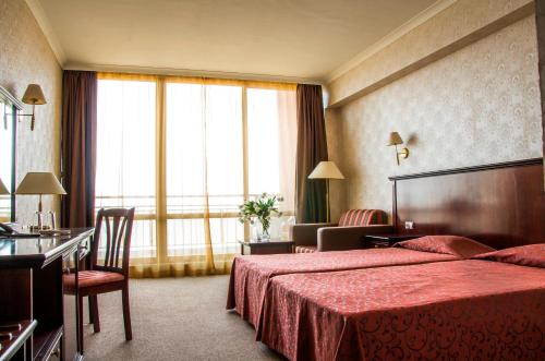 a hotel room with a red bed and a large window at Gladiola 4-star in Golden Sands