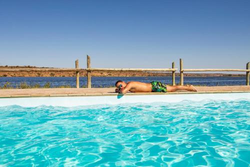 a woman laying on the edge of a swimming pool at Chobe River Campsite in Ngoma