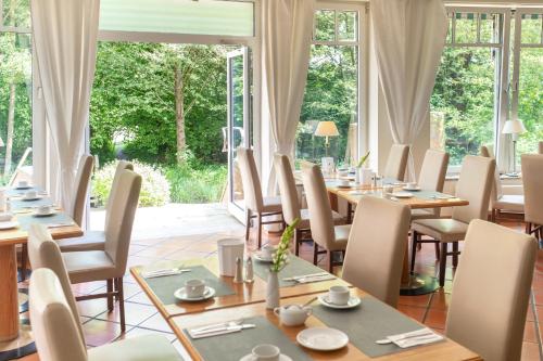 a dining room with tables and chairs and windows at Hotel Lübecker Hof in Lübeck