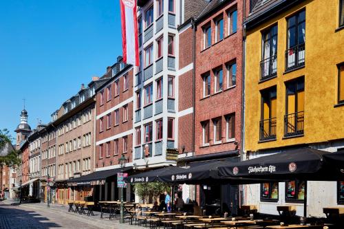 a row of buildings with tables and umbrellas on a street at Hotel Kö59 Düsseldorf - Member of Hommage Luxury Hotels Collection in Düsseldorf