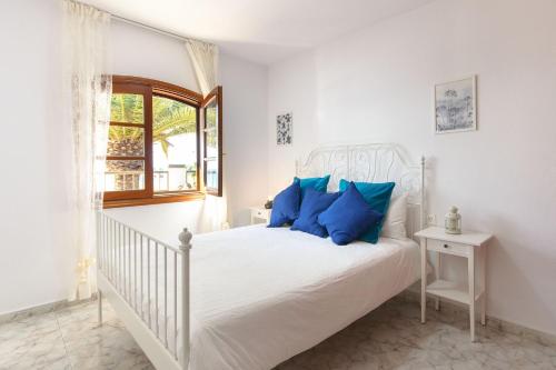 Un dormitorio blanco con una cama blanca con almohadas azules. en Salitre, en Playa Honda
