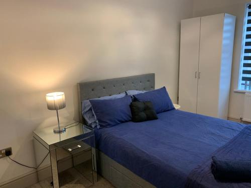 Schlafzimmer mit einem Bett mit blauer Bettwäsche und einer Lampe in der Unterkunft Margate's Modern Luxury Apartment in Margate