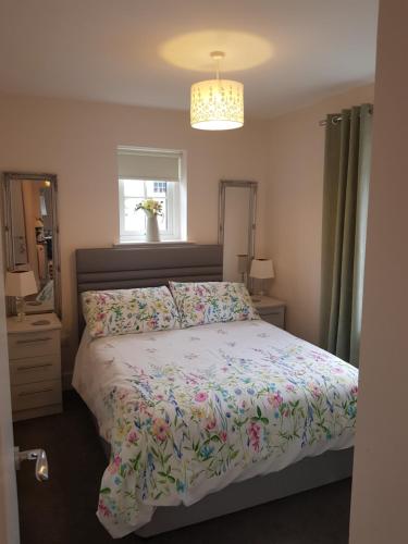 a bedroom with a bed with a floral comforter at Olavat Cottage detached property with parking in Inverness