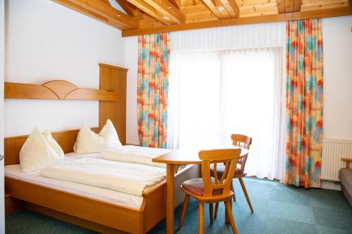 1 dormitorio con 1 cama, mesa y sillas en Erlebnishotel Kärnten-Mölltal 3 Stern Superior, en Obervellach