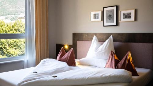 a hotel room with a bed with pillows and a window at City Hotel Merano in Merano
