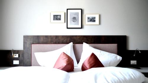 a bedroom with two beds with white and red pillows at City Hotel Merano in Merano