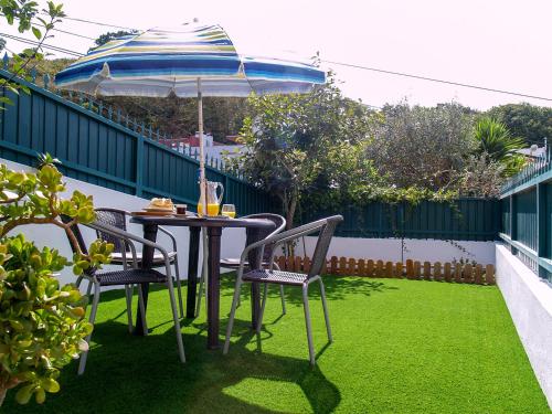 a table and chairs with an umbrella on a lawn at Apartamento Sintra in Sintra