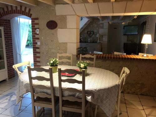 a dining room table with chairs and a kitchen at Gite de la Pilaudière in Thésée
