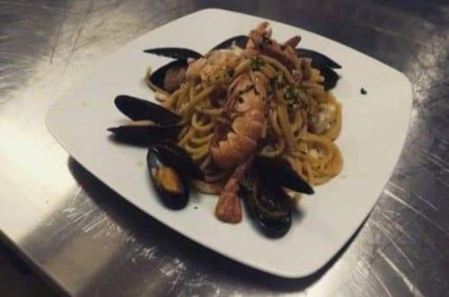 a white plate of food with pasta and mussels at Hotel Mariagrazia in Calopezzati