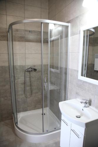 a shower with a glass door next to a sink at Pokoje nad Nysą Olszyna in Olszyna