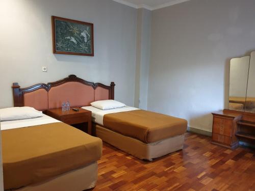 a hotel room with two beds and a mirror at Yehezkiel Hotel Lembang Mitra RedDoorz in Bandung