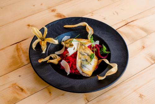 a black plate with food on a wooden table at Hotel Veverica in Trenčín