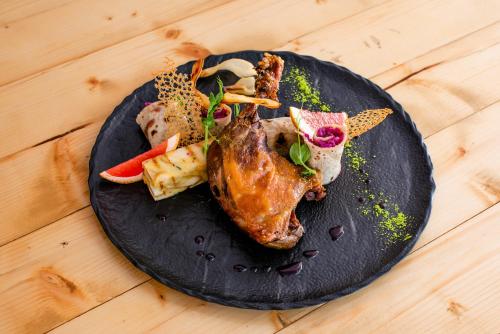 a black plate with meat and vegetables on a wooden table at Hotel Veverica in Trenčín