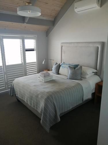 a bedroom with a large white bed with a window at Linhof Boutique Guest House in Paternoster
