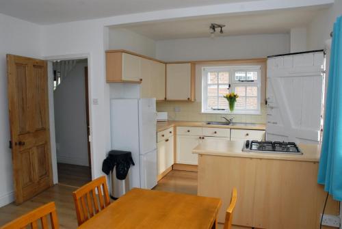una cucina con tavolo e frigorifero bianco di Greysfield Cottage a Chester