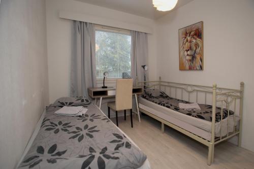 a bedroom with two beds and a desk and a table at KOLMIO SAUNALLA in Kokkola
