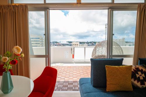 a living room with a couch and a table and a balcony at Hotel Tomas Asahibashi Station in Naha