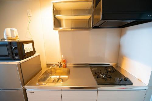 a small kitchen with a stove and a microwave at Hotel Tomas Asahibashi Station in Naha