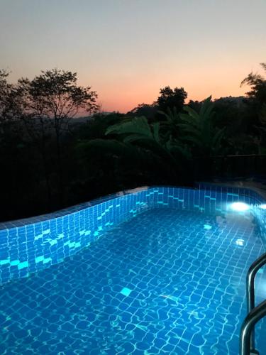 a large blue swimming pool with a sunset in the background at Tafelberg detached bungalow with swimming pool in Chiang Rai