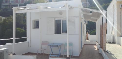 een wit huis met een tafel en stoelen op een balkon bij Apostolakis Rooms in Agios Kirykos