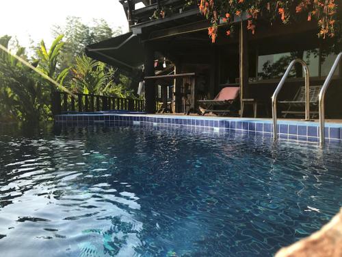 a swimming pool in front of a house at Tafelberg detached bungalow with swimming pool in Chiang Rai
