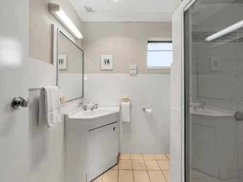 a white bathroom with a sink and a shower at Yamba Sun Motel in Yamba