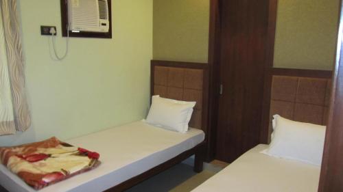 Habitación pequeña con 2 camas y ventilador. en Bhammar's Inn - A Pure Veg en Calcuta
