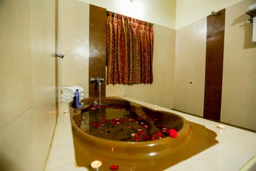 a bathroom with a tub with red flowers in it at Hotel Abi's Inn in Thanjāvūr