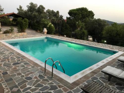 a swimming pool with blue water in a yard at Villa Maroudia in Kymi