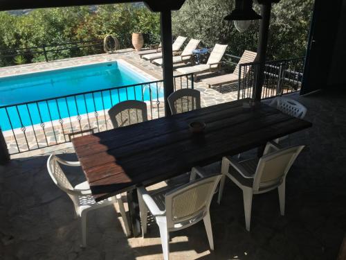 a wooden table and chairs next to a swimming pool at Villa Maroudia in Kymi