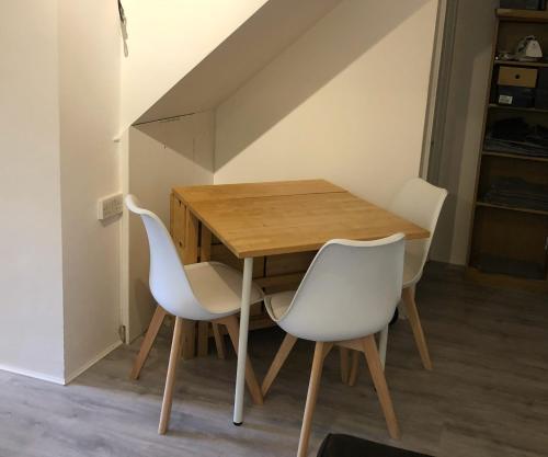 a wooden table and two white chairs in a room at Double Room with Private Bathroom in a 2-bedrooms house in London