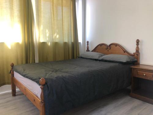 1 dormitorio con cama con marco de madera y ventana en Double Room with Private Bathroom in a 2-bedrooms house en Londres