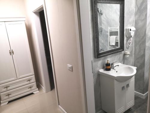 a white bathroom with a sink and a mirror at YNS Rooms in Iaşi
