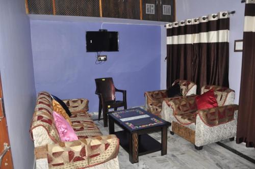 a living room with couches and a flat screen tv at Green Hill in Mount Ābu