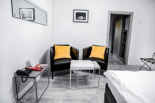 a room with two chairs and a table and a bed at Hotel Gong in Štramberk