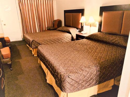 a hotel room with two beds and a desk at Red Carpet Inn & Suites in Calgary