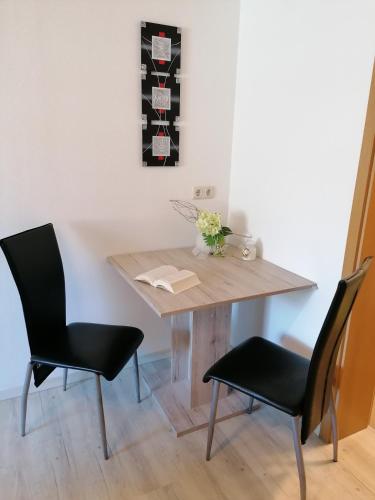 a dining room table with two black chairs and a wooden table at Apartment Weber in Offenheim