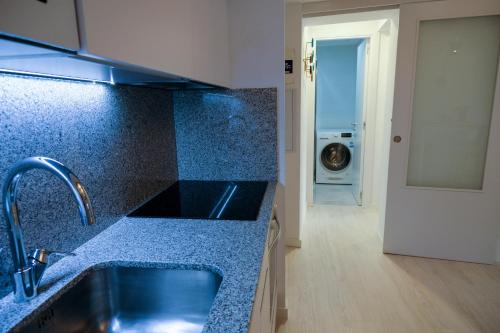 a kitchen with a sink and a washing machine at Silken Casa Platerias Siglo XV in Zaragoza