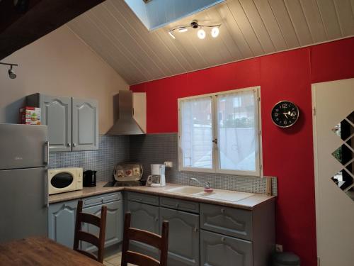 eine Küche mit roten Wänden, einer Spüle und einem Kühlschrank in der Unterkunft Maison proche plage avec terrasse ensoleillée in Dunkerque