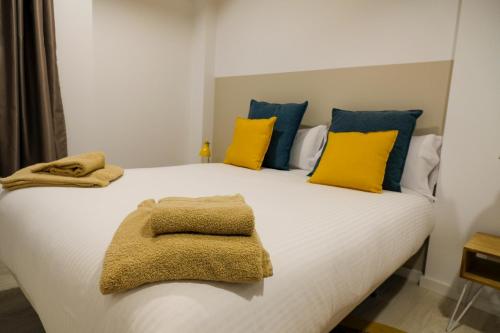 a large white bed with yellow and blue pillows at Silken Casa Platerias Siglo XV in Zaragoza