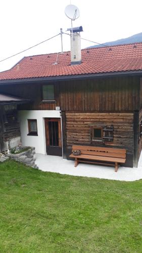 a wooden building with a bench in front of it at Ferienhäuschen Rahm in Hainzenberg
