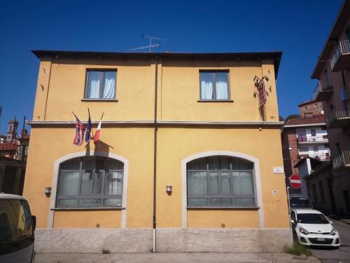 ein gelbes Gebäude mit zwei Fenstern und zwei Flaggen darauf in der Unterkunft Hotel Cavour Resort in Moncalieri