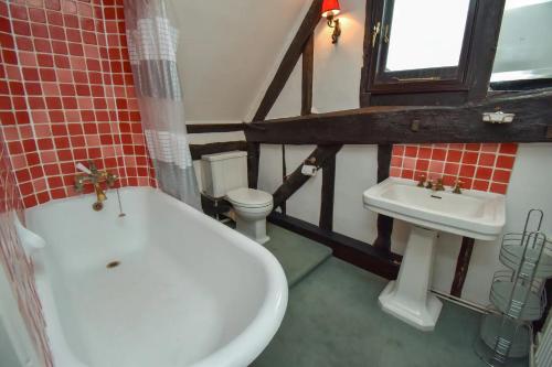 La salle de bains est pourvue de toilettes, d'une baignoire et d'un lavabo. dans l'établissement The Game Keepers Cottage, à Welwyn