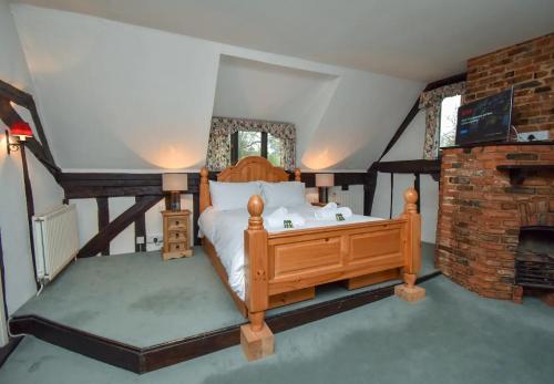 a bedroom with a wooden bed and a fireplace at The Game Keepers Cottage in Welwyn