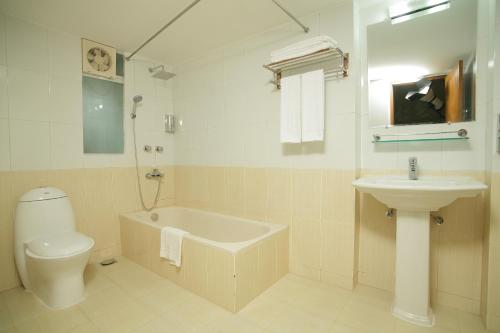a bathroom with a sink and a tub and a toilet at Richmond Hotel & Suites in Dhaka