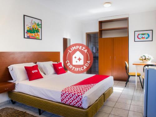 1 dormitorio con 1 cama grande con almohadas rojas en OYO Athenas Apart Hotel, en Campo Grande