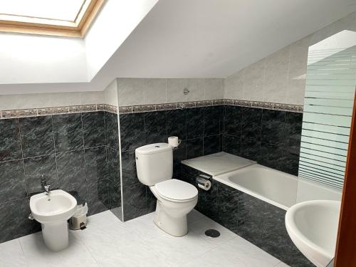 a bathroom with a toilet and a sink and a bath tub at Hotel - Apartamentos Peña Santa in Onís