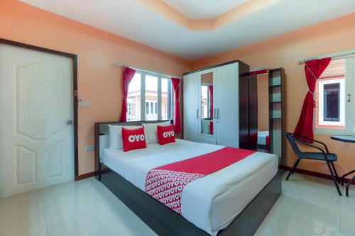 OYO 1166 Train Way Resort في Ban Laem Chabang: غرفة نوم بسرير كبير ومخدات حمراء