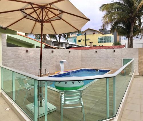 a swimming pool with a table and an umbrella at Casa com Piscina em Ingleses, para 09 pessoas in Florianópolis
